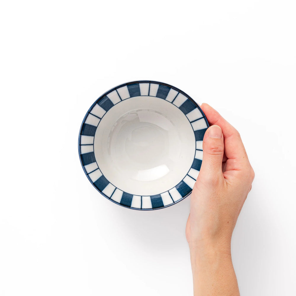 Japanese porcelain rice bowl with bold indigo and white stripe pattern and terracotta base, crafted in modern traditional style.