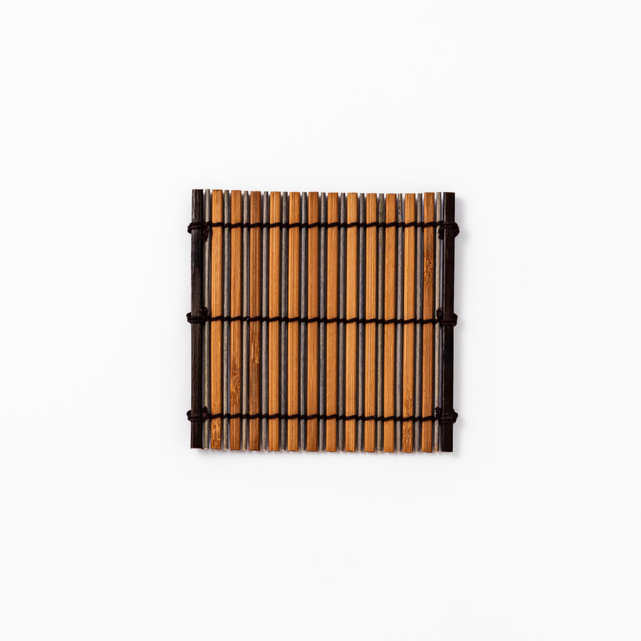 Brown bamboo coaster with alternating natural and dark slats, bound with black cord, adding a rustic and refined touch to Japanese-style tableware.