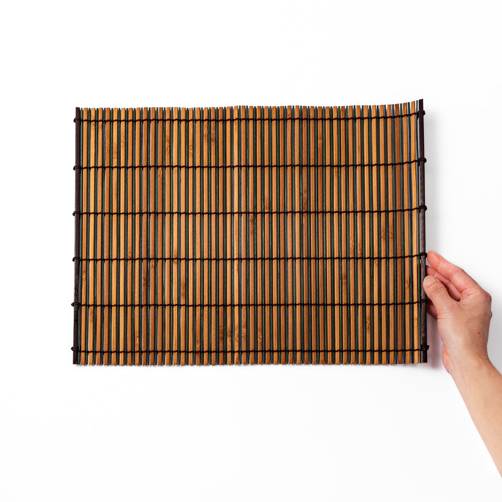 Brown bamboo table mat featuring alternating dark and natural slats bound with black cord, perfect for warm, earthy Japanese-inspired table settings.