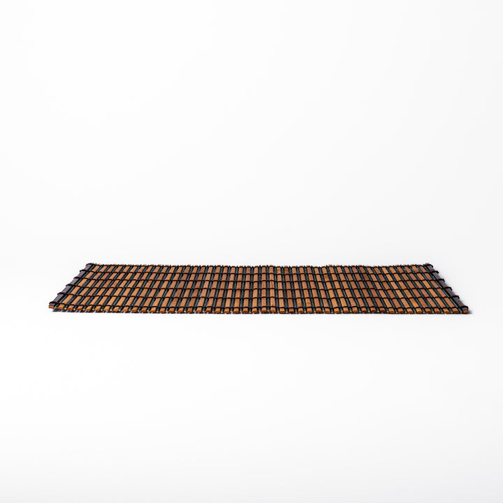 Brown bamboo table mat featuring alternating dark and natural slats bound with black cord, perfect for warm, earthy Japanese-inspired table settings.