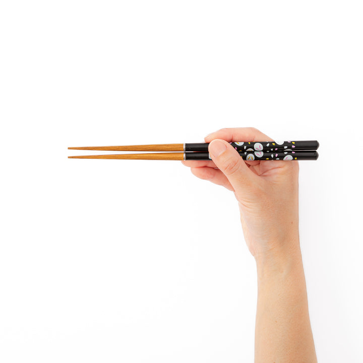 A hand holding assembled portable Japanese travel chopsticks to demonstrate the proper length and natural comfortable grip