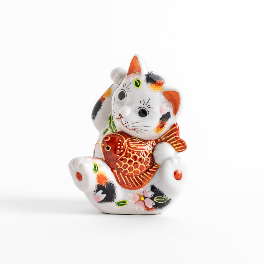 Colorful Calico Maneki Neko figurine holding a lucky sea bream, adorned with floral and green leaf patterns, symbolizing good fortune and prosperity in Japanese culture.