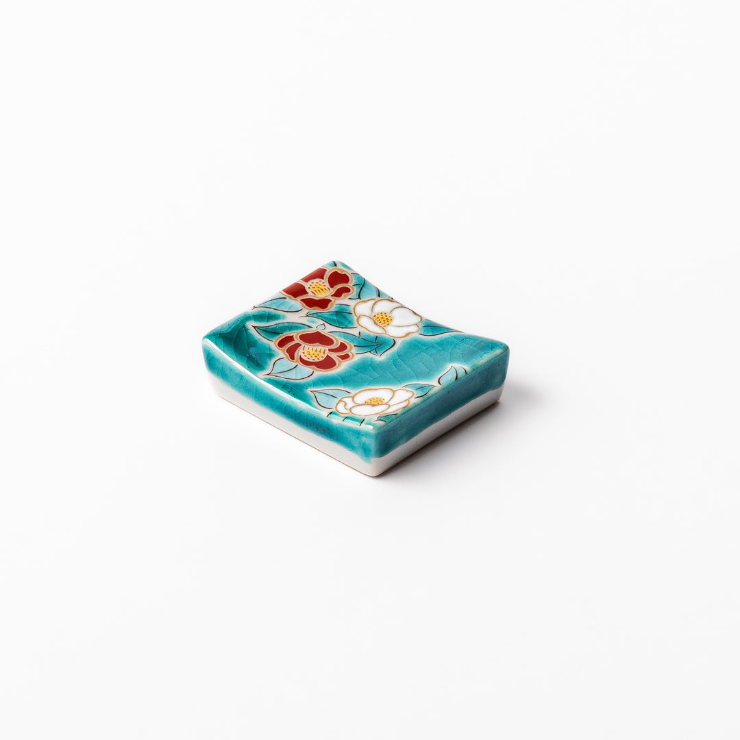 Japanese ceramic chopstick rest featuring red and white camellia blossom design on a glossy teal background, perfect for enhancing elegant table settings.