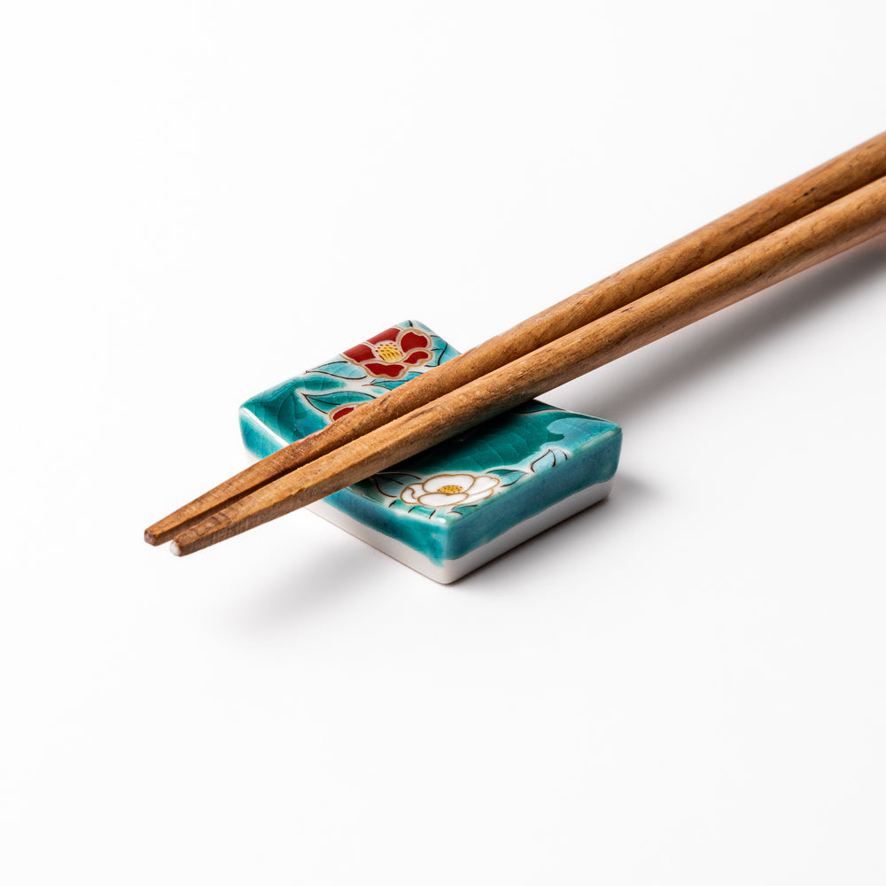 Japanese ceramic chopstick rest featuring red and white camellia blossom design on a glossy teal background, perfect for enhancing elegant table settings.