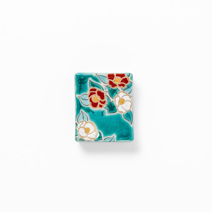 Japanese ceramic chopstick rest featuring red and white camellia blossom design on a glossy teal background, perfect for enhancing elegant table settings.