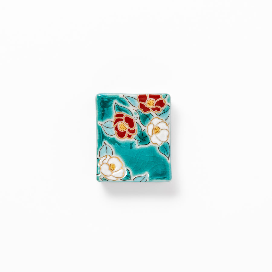 Japanese ceramic chopstick rest featuring red and white camellia blossom design on a glossy teal background, perfect for enhancing elegant table settings.
