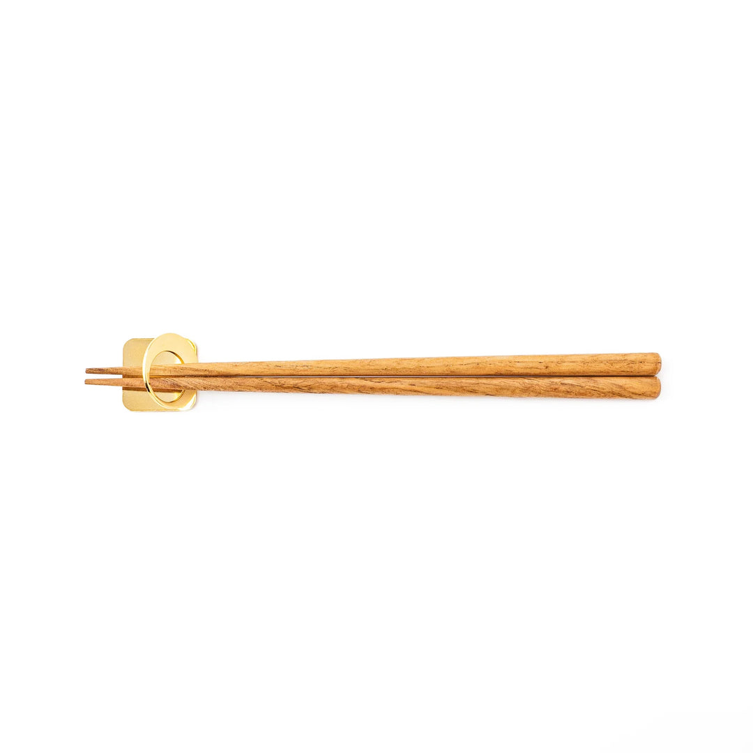 Wooden chopsticks resting on a celestial gold circle moon chopstick holder minimalist Japanese table setting hashioki