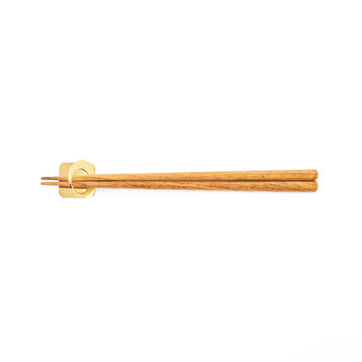 Wooden chopsticks resting on a celestial gold circle moon chopstick holder minimalist Japanese table setting hashioki