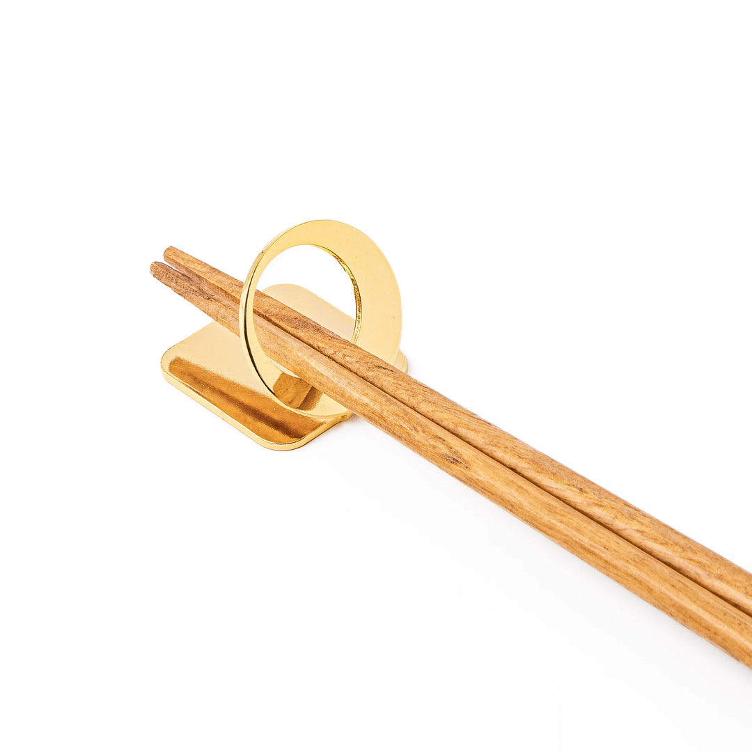 Wooden chopsticks resting on a celestial gold circle moon chopstick holder minimalist Japanese table setting hashioki