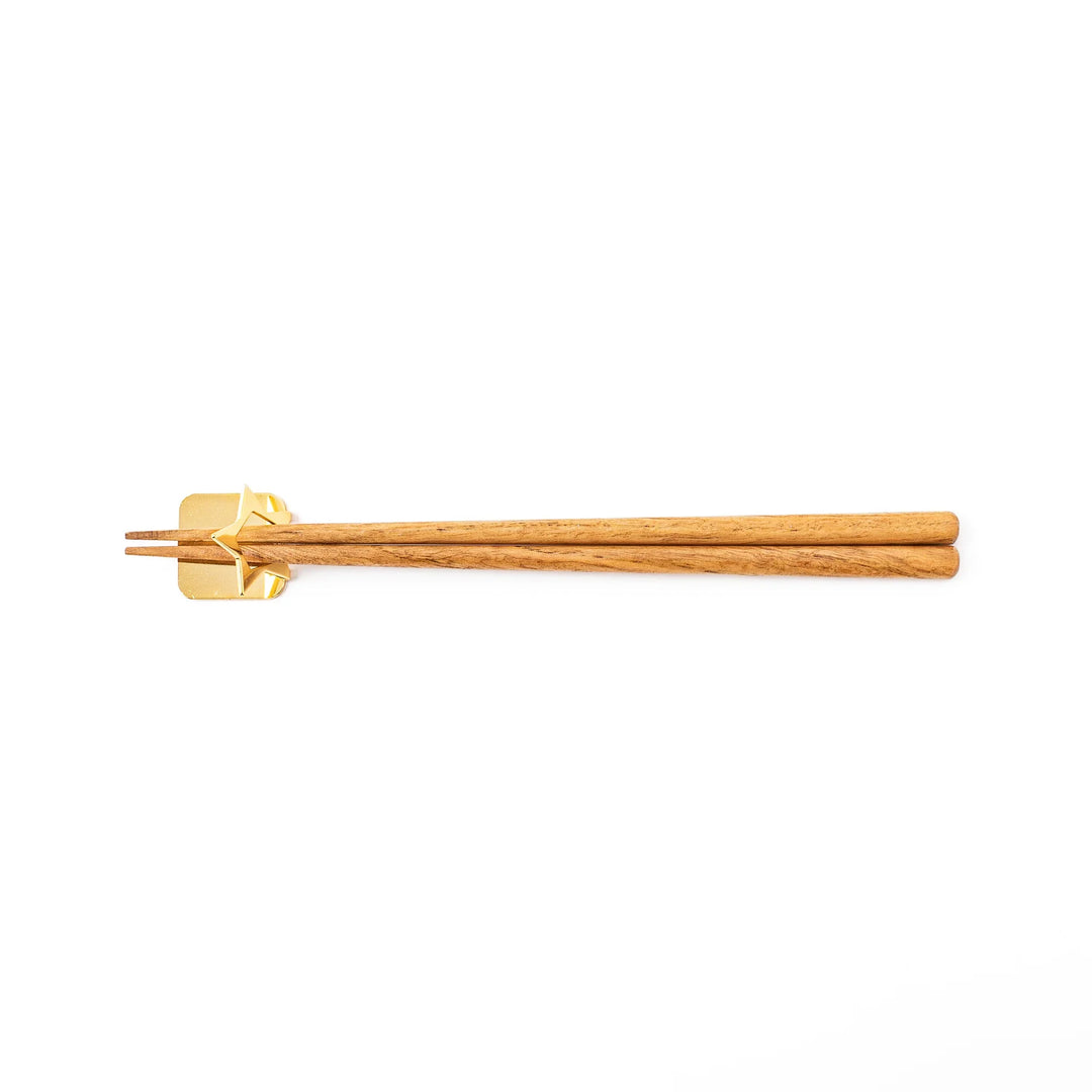 Wooden chopsticks resting on a celestial gold star chopstick holder minimalist Japanese table setting hashioki