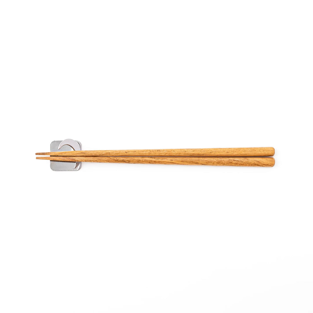 Wooden chopsticks resting on a celestial silver crescent moon chopstick holder minimalist Japanese table setting hashioki