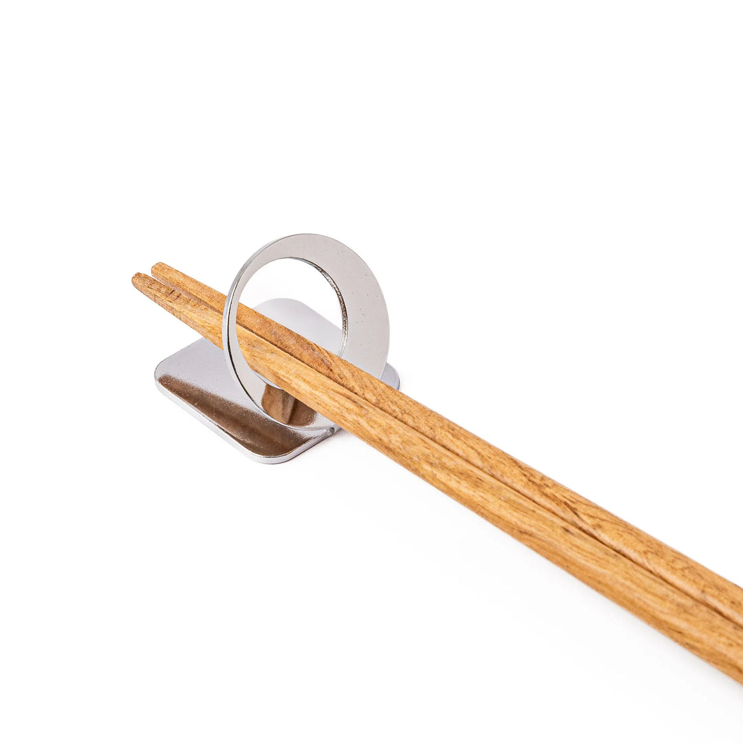 Wooden chopsticks resting on a celestial silver circle moon chopstick holder minimalist Japanese table setting hashioki
