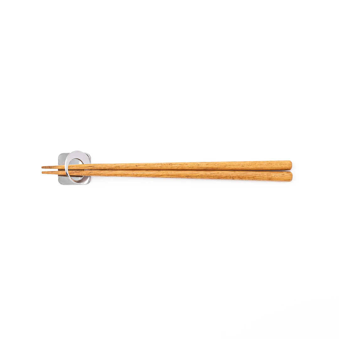 Wooden chopsticks resting on a celestial silver circle moon chopstick holder minimalist Japanese table setting hashioki