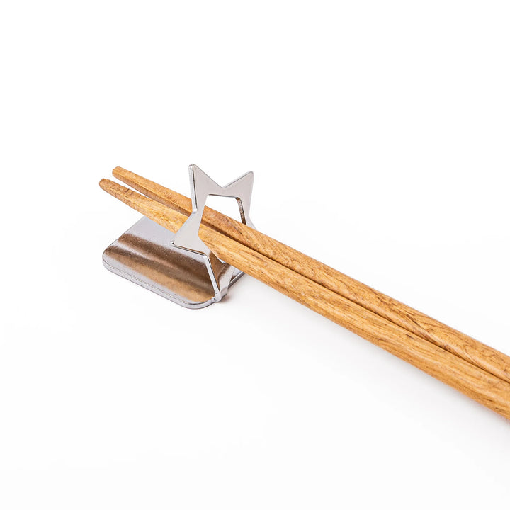 Wooden chopsticks resting on a celestial silver star chopstick holder minimalist Japanese table setting hashioki
