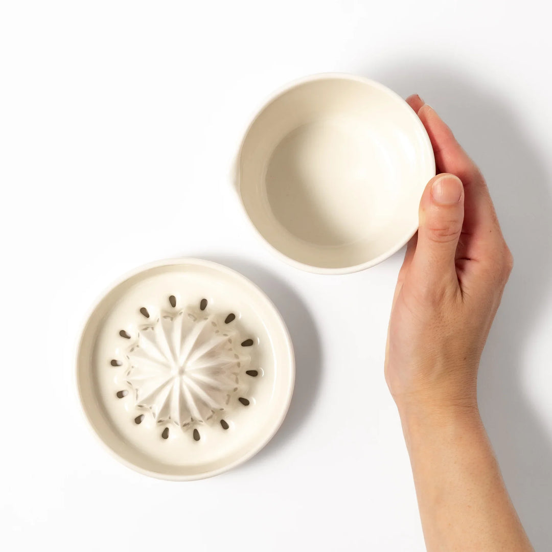 White ceramic citrus juicer with ridged reamer and built-in strainer, designed for effortlessly extracting juice from lemons, limes, and other citrus fruits.