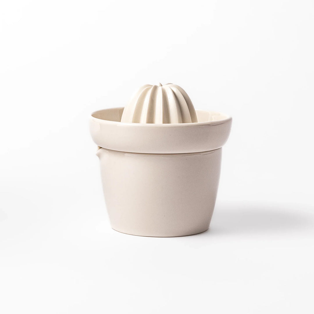 White ceramic citrus juicer with ridged reamer and built-in strainer, designed for effortlessly extracting juice from lemons, limes, and other citrus fruits.