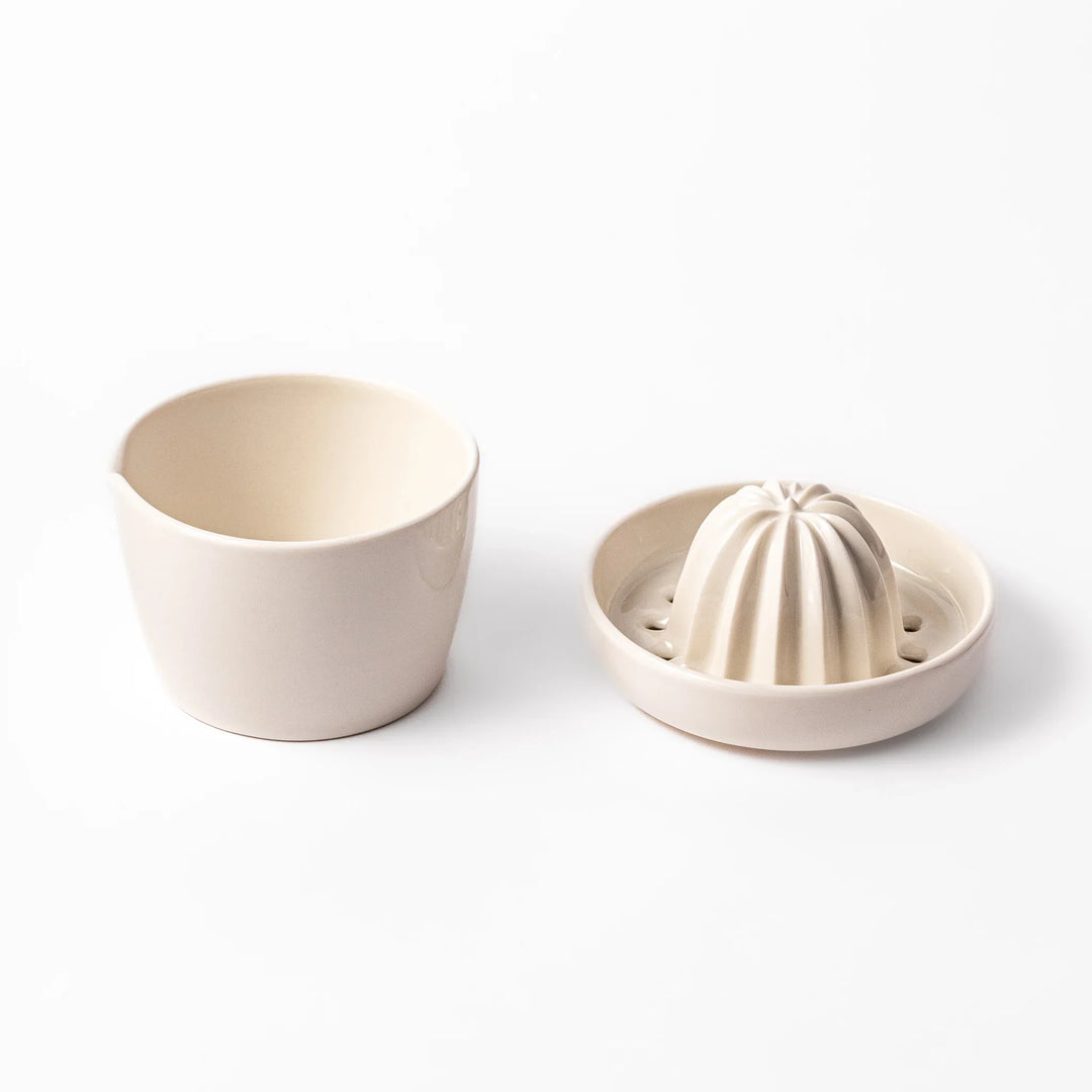 White ceramic citrus juicer with ridged reamer and built-in strainer, designed for effortlessly extracting juice from lemons, limes, and other citrus fruits.