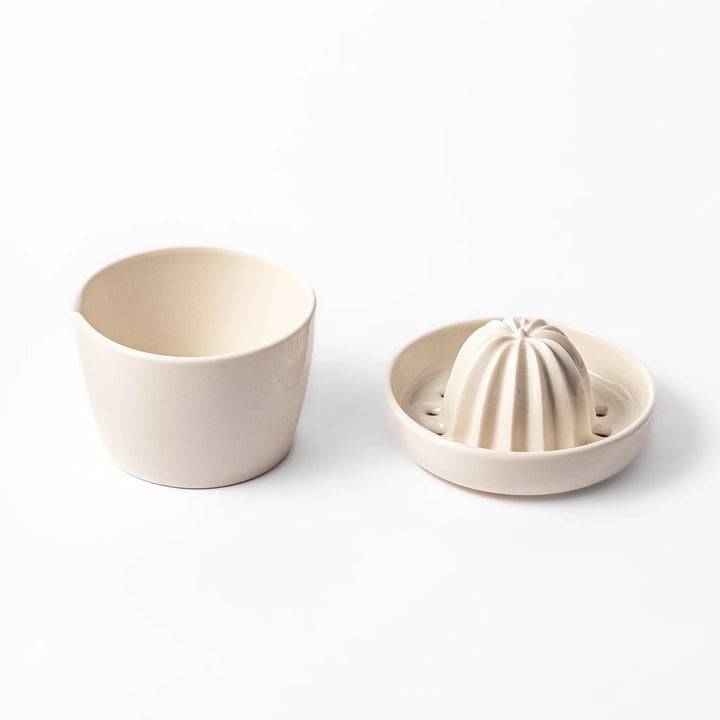White ceramic citrus juicer with ridged reamer and built-in strainer, designed for effortlessly extracting juice from lemons, limes, and other citrus fruits.