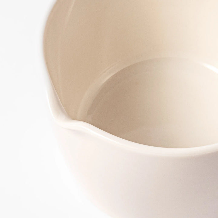 White ceramic citrus juicer with ridged reamer and built-in strainer, designed for effortlessly extracting juice from lemons, limes, and other citrus fruits.