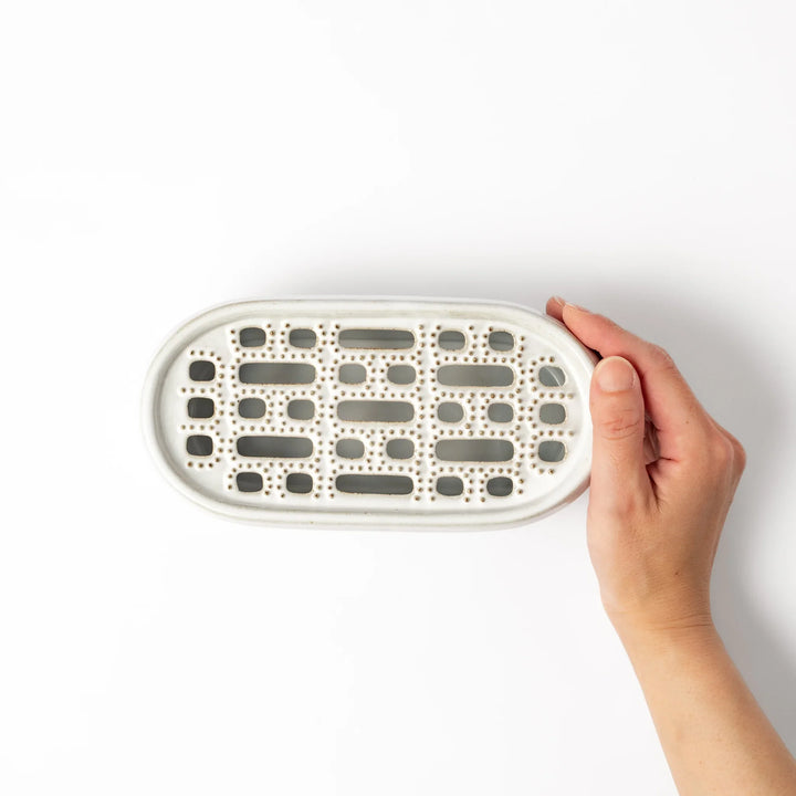 White ceramic daikon oroshi grater with built-in dish and wide grating holes, perfect for smoothly preparing grated daikon, ginger, or root vegetables.