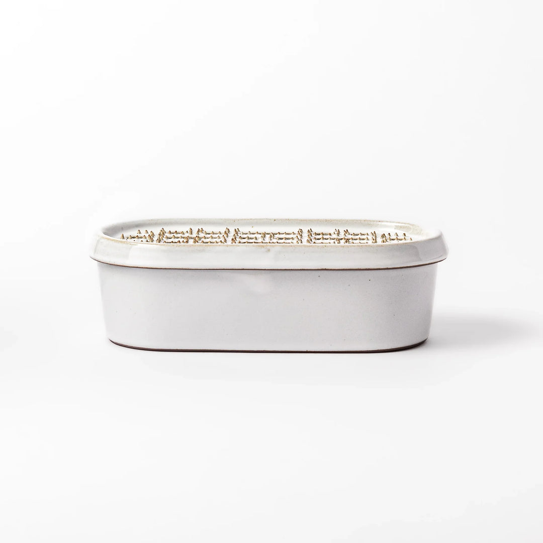 White ceramic daikon oroshi grater with built-in dish and wide grating holes, perfect for smoothly preparing grated daikon, ginger, or root vegetables.