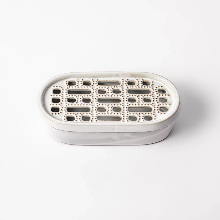 White ceramic daikon oroshi grater with built-in dish and wide grating holes, perfect for smoothly preparing grated daikon, ginger, or root vegetables.