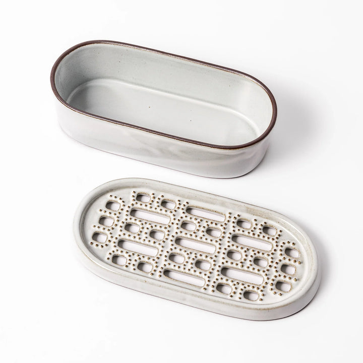 White ceramic daikon oroshi grater with built-in dish and wide grating holes, perfect for smoothly preparing grated daikon, ginger, or root vegetables.
