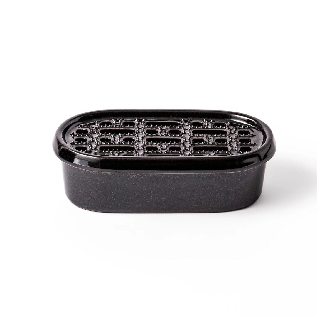 Black ceramic daikon oroshi grater with built-in serving dish, featuring wide grating holes and textured surface for smooth grating and easy cleanup.