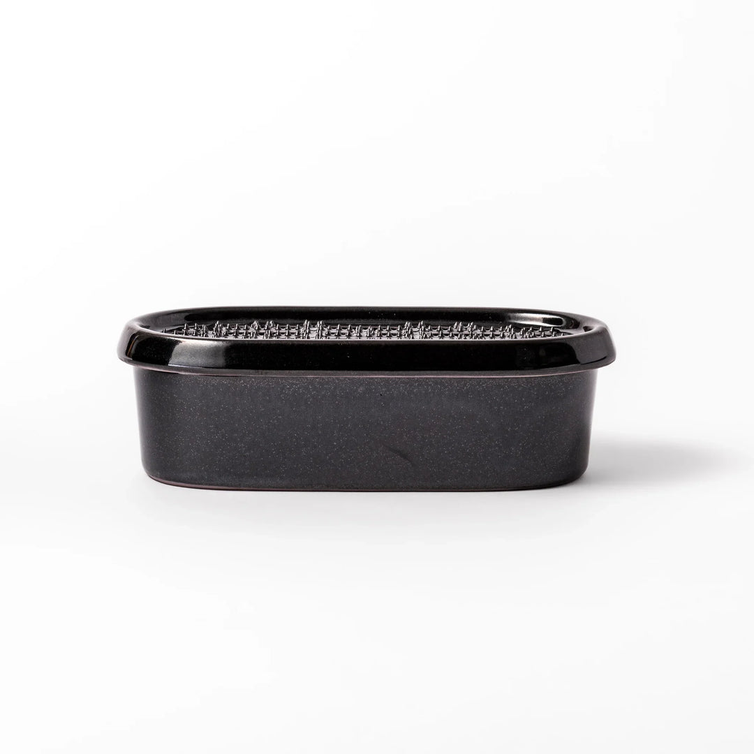 Black ceramic daikon oroshi grater with built-in serving dish, featuring wide grating holes and textured surface for smooth grating and easy cleanup.