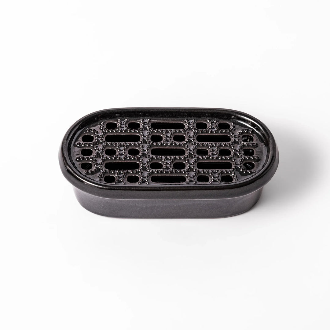Black ceramic daikon oroshi grater with built-in serving dish, featuring wide grating holes and textured surface for smooth grating and easy cleanup.