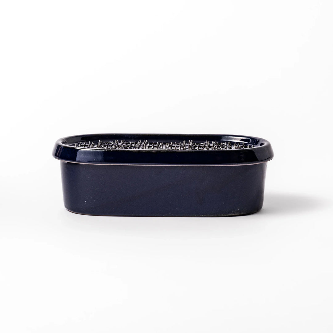 Deep blue ceramic daikon oroshi grater with an integrated serving dish, featuring wide grating holes and raised texture for easy grating and cleanup.