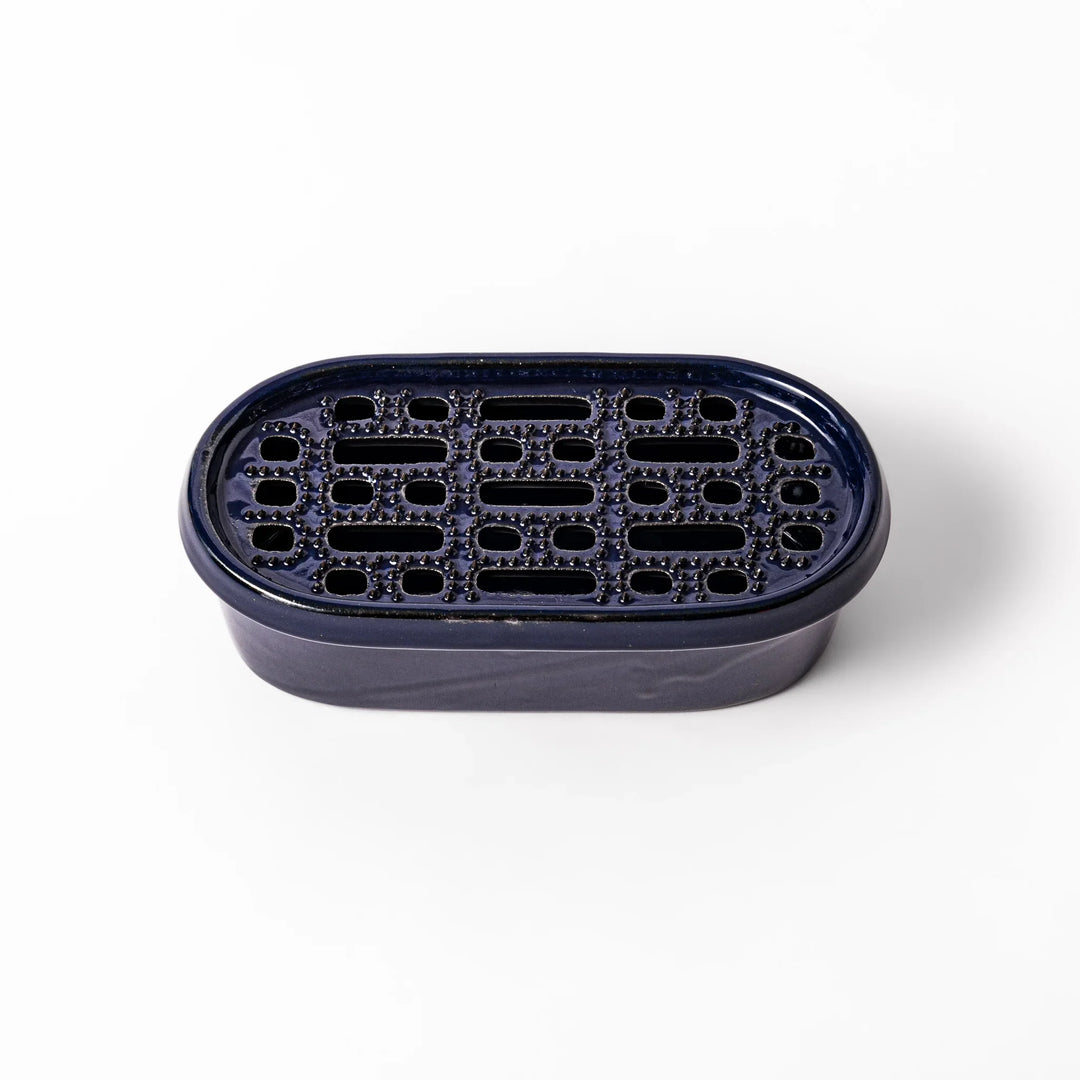 Deep blue ceramic daikon oroshi grater with an integrated serving dish, featuring wide grating holes and raised texture for easy grating and cleanup.