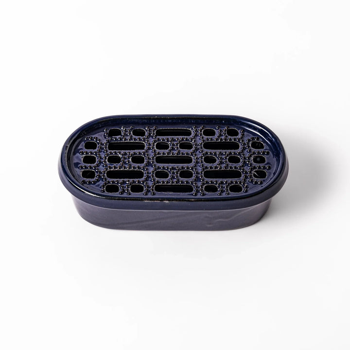 Deep blue ceramic daikon oroshi grater with an integrated serving dish, featuring wide grating holes and raised texture for easy grating and cleanup.