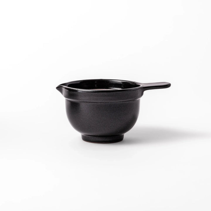 Black ceramic natto suribachi bowl with a ridged brown interior and side handle, ideal for grinding and mixing natto or other small ingredients.