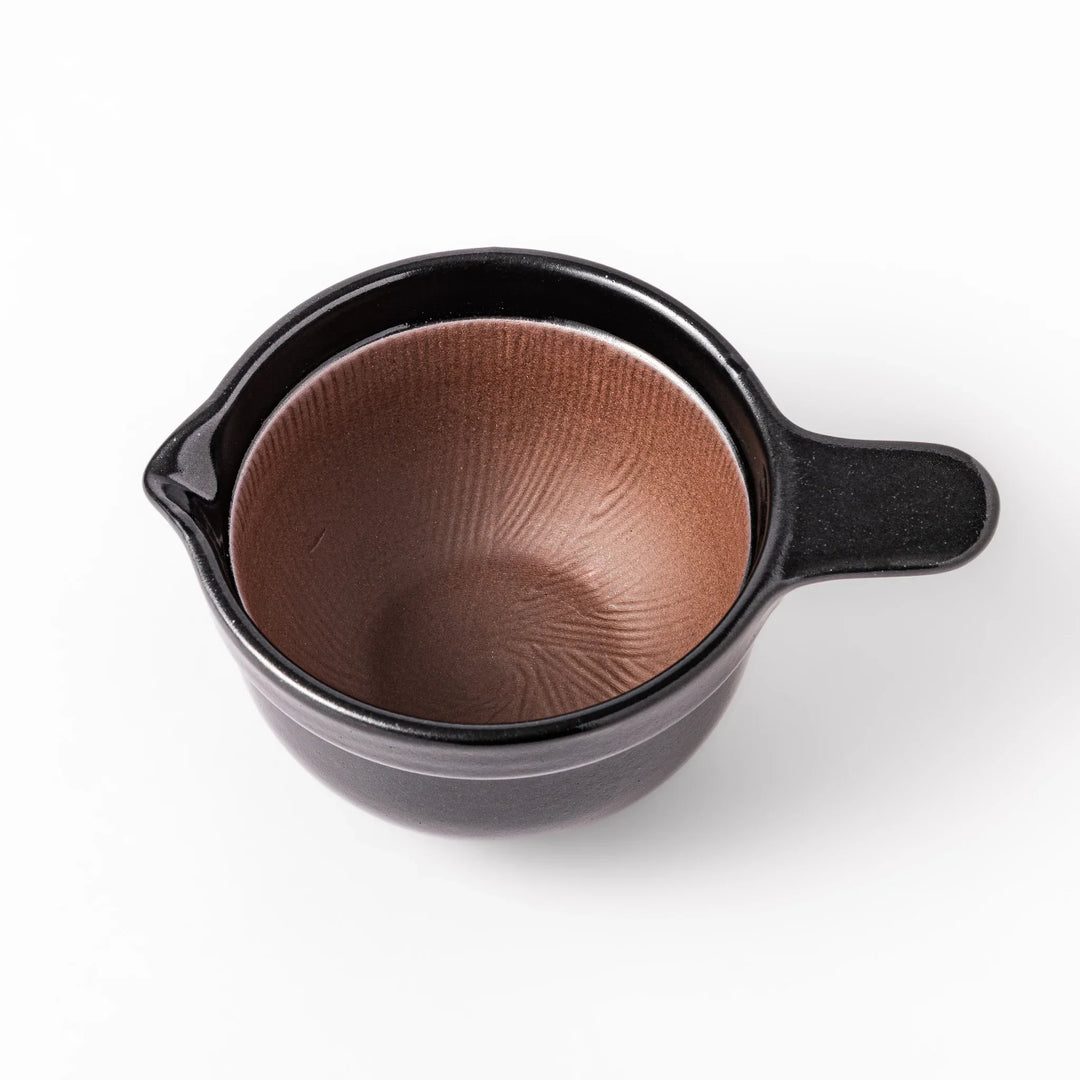 Black ceramic natto suribachi bowl with a ridged brown interior and side handle, ideal for grinding and mixing natto or other small ingredients.