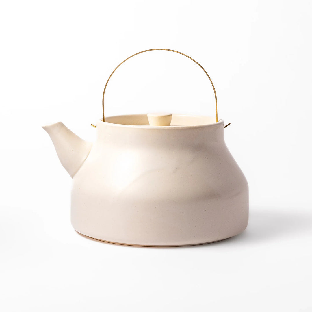 White ceramic stovetop kettle with a smooth matte finish and brass handle, blending traditional charm with modern function for daily tea rituals.