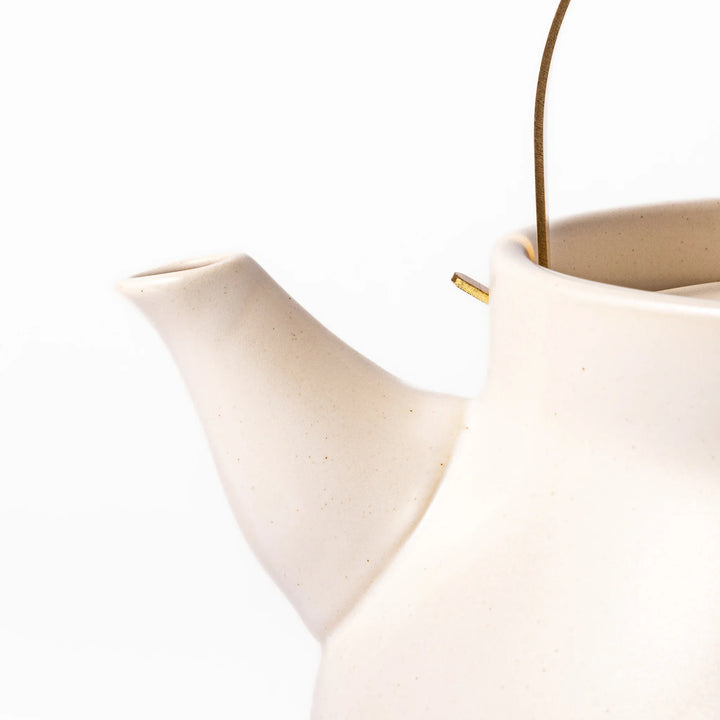 White ceramic stovetop kettle with a smooth matte finish and brass handle, blending traditional charm with modern function for daily tea rituals.