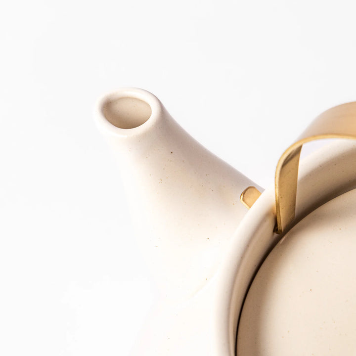 White ceramic stovetop kettle with a smooth matte finish and brass handle, blending traditional charm with modern function for daily tea rituals.