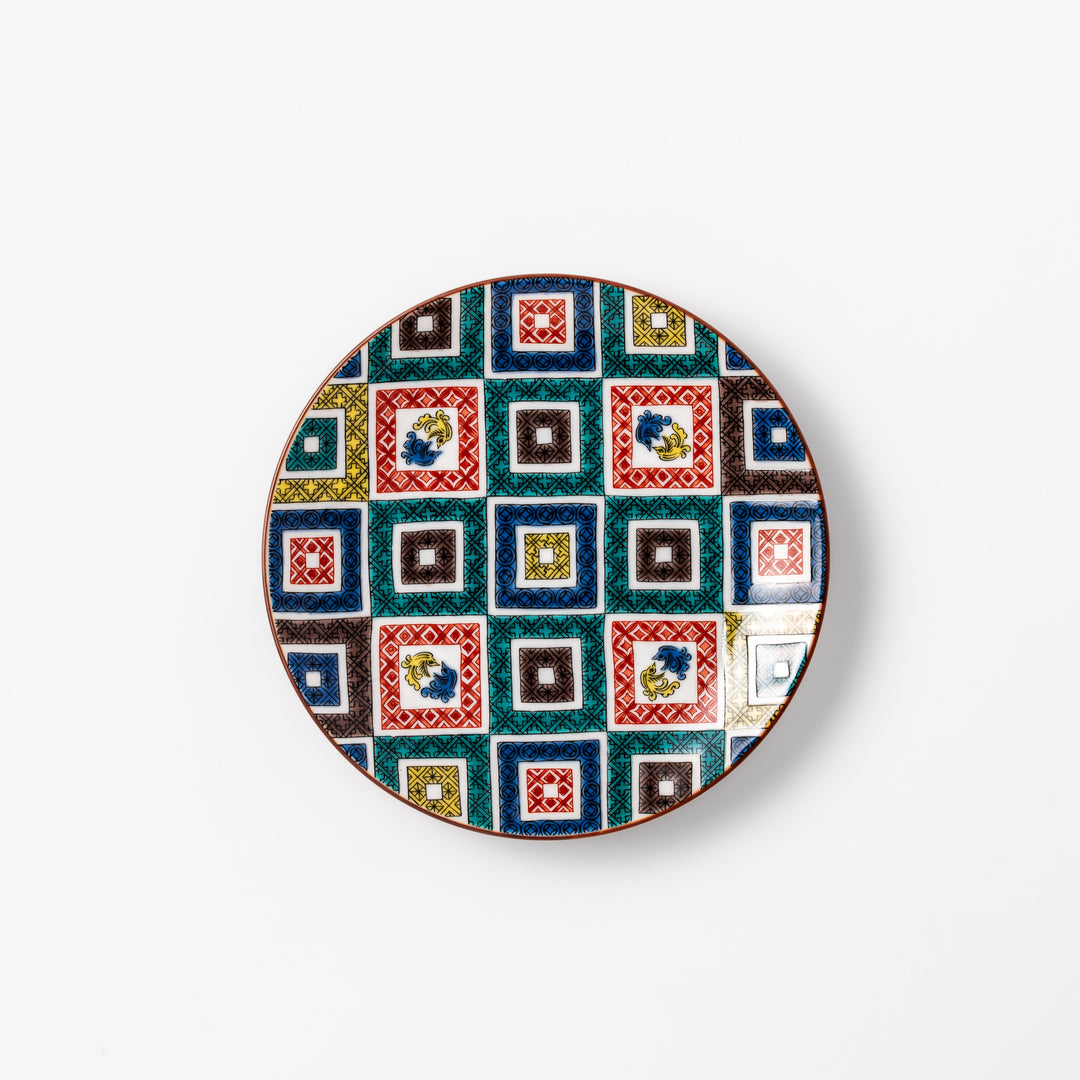 Colorful porcelain dessert plate featuring a mosaic of geometric square patterns in red, green, yellow, blue, and black with floral accents.