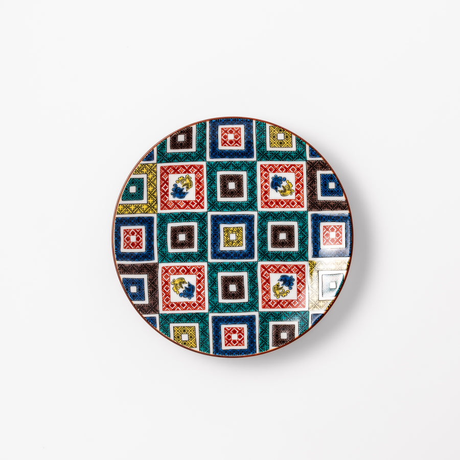 Colorful porcelain dessert plate featuring a mosaic of geometric square patterns in red, green, yellow, blue, and black with floral accents.