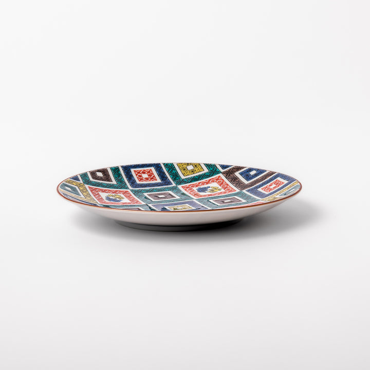 Colorful porcelain dessert plate featuring a mosaic of geometric square patterns in red, green, yellow, blue, and black with floral accents.