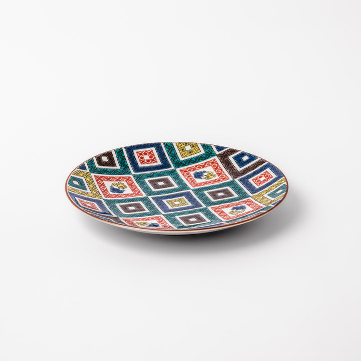 Colorful porcelain dessert plate featuring a mosaic of geometric square patterns in red, green, yellow, blue, and black with floral accents.