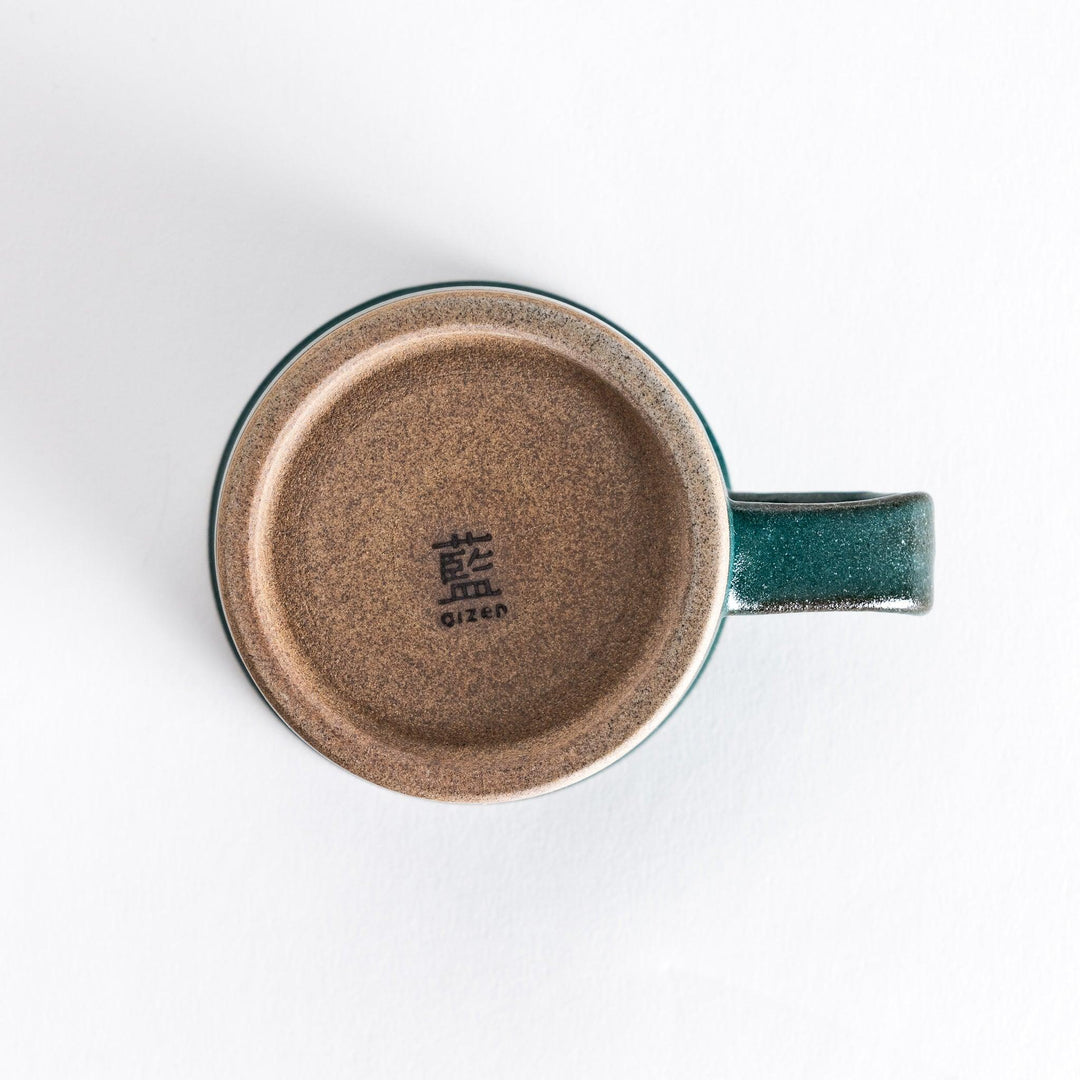 Bottom view of a green ceramic mug featuring a smooth neutral-toned base with a light texture that contrasts the glossy green.