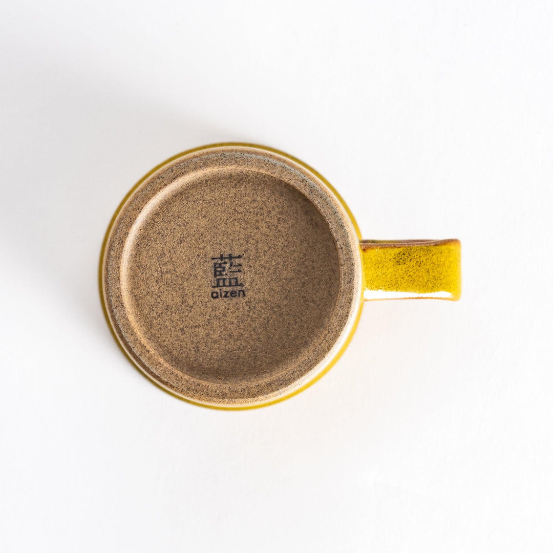 Bottom view of a yellow ceramic mug featuring a neutral-toned base with a subtle texture that complements the bright yellow glaze.