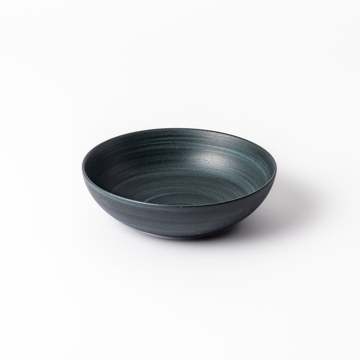 Deep navy ceramic bowl with subtle concentric lines and matte finish, softly flared rim against a white background