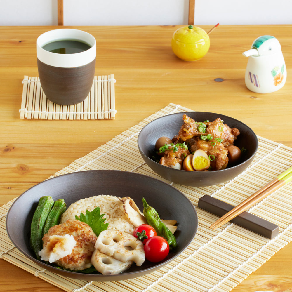 Modern brown dinnerware set featuring rice with vegetables and chicken stew, styled on a bamboo mat for a warm Japanese dining table.