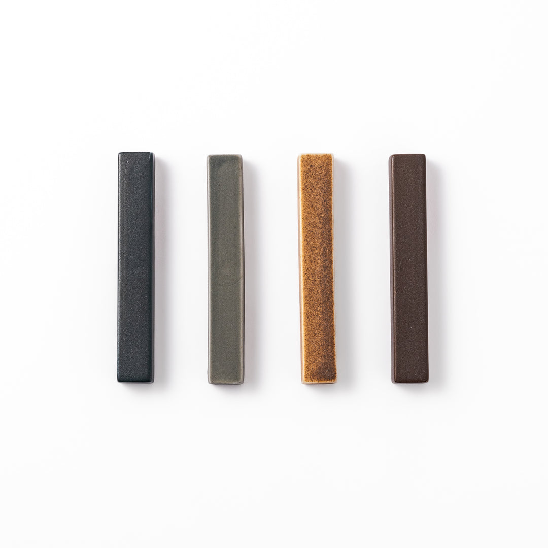 Rectangular ceramic chopstick rests in four earthy Japandi tones arranged diagonally in navy, gray, beige, and brown