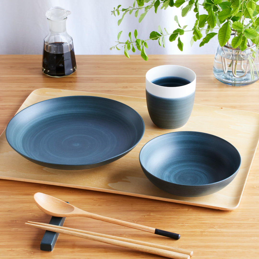 Elegant navy blue dinnerware set with gradient design, including plate, bowl, and cup, paired with wooden chopsticks and spoon.