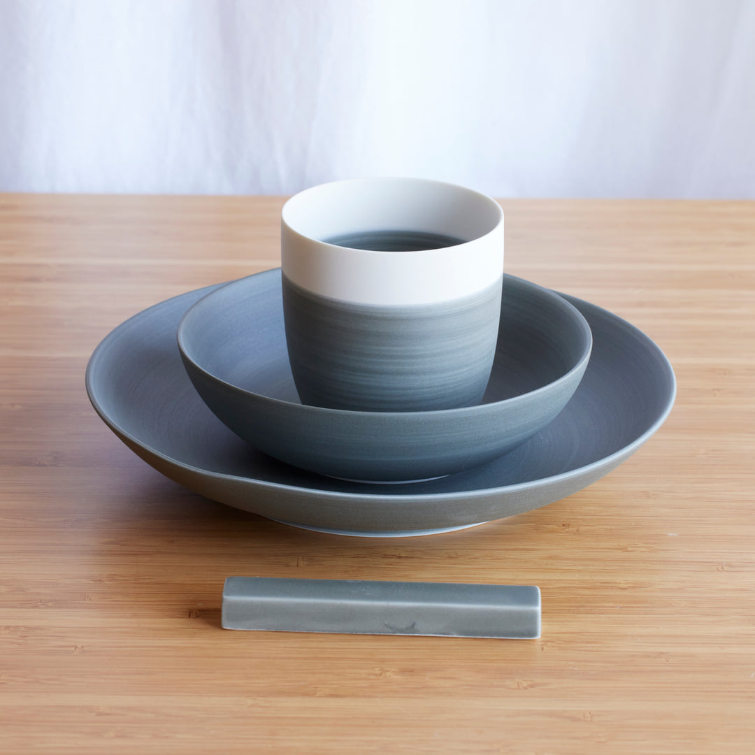 Minimalist Japandi 4-Piece Dinnerware Set in gray, neatly stacked with plate, bowl, and cup, alongside a matching chopstick rest.