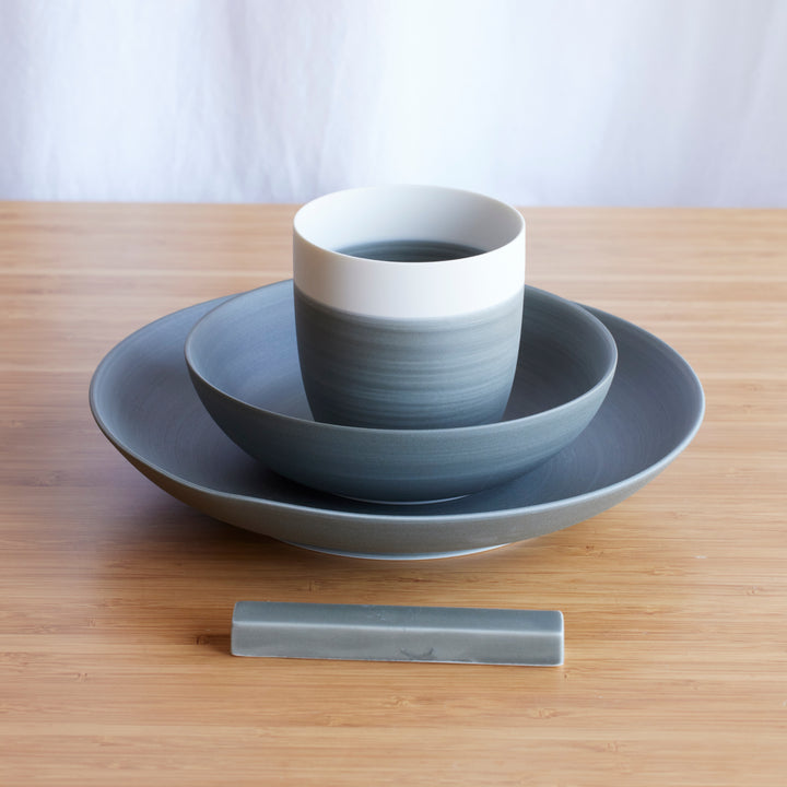 Minimalist Japandi 4-Piece Dinnerware Set in gray, neatly stacked with plate, bowl, and cup, alongside a matching chopstick rest.
